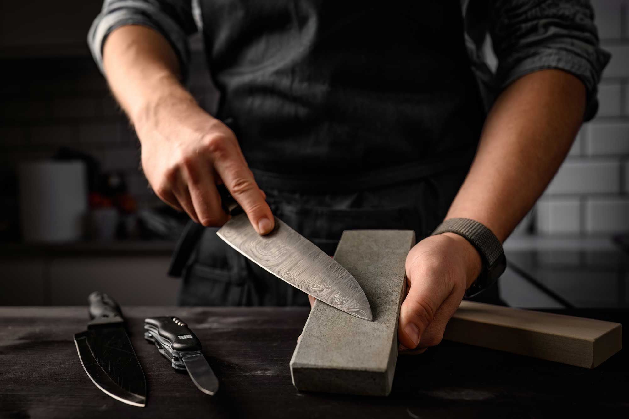 Persona afilando cuchillo de cocina con una piedra de afilar 